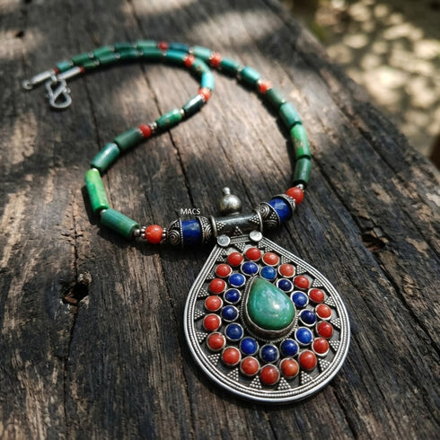 Colorful turquoise beaded necklace with a decorative lapis coral pendant on a wooden surface
