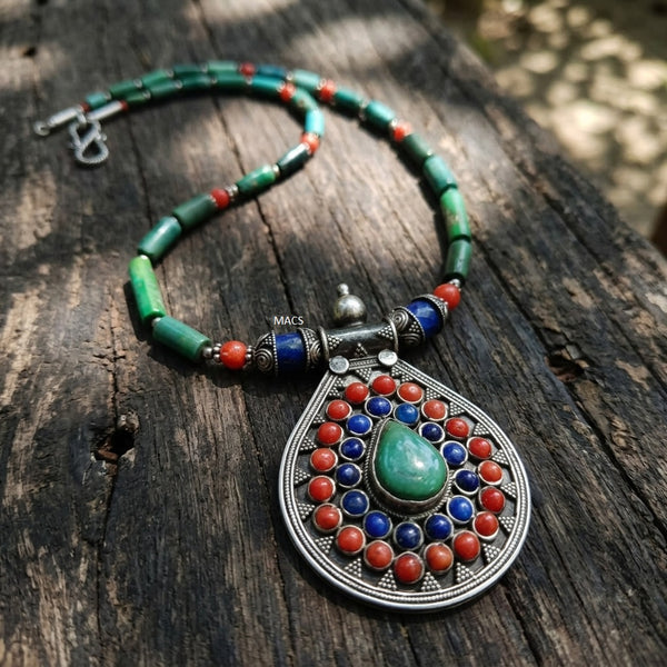 Colorful turquoise beaded necklace with a decorative lapis coral pendant on a wooden surface