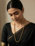Woman wearing a black saree with gold plated dholki mala