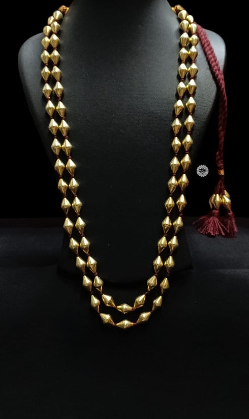 Gold plated layered dholki beaded necklace on a black mannequin