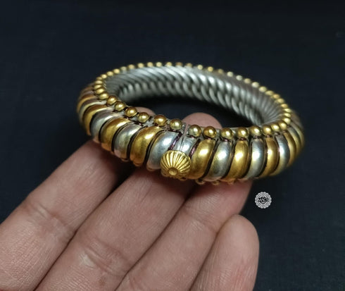 Gold and silver dual tone bangle held on a hand. Dual tone 925 silver kada