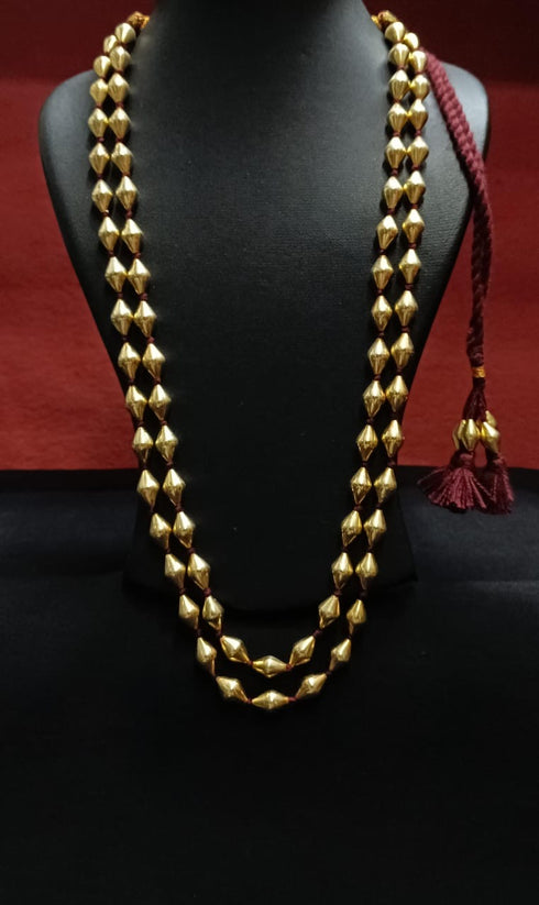 Gold dholki beaded necklace on a black mannequin