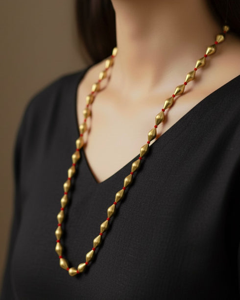 Gold plated dholki necklace with handcrafted red thread worn by a person