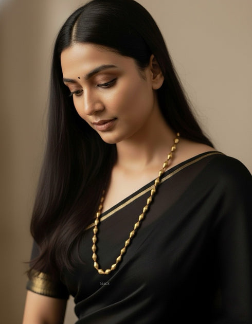 Woman wearing a black saree with gold plated dholki single layered long necklace