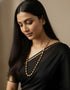 Woman wearing a black saree with gold plated dholki single layered long necklace