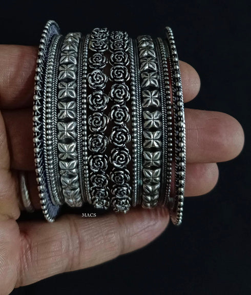 a stack of ornate 925 pure silver bangles with intricate floral and geometric embossed patterns
