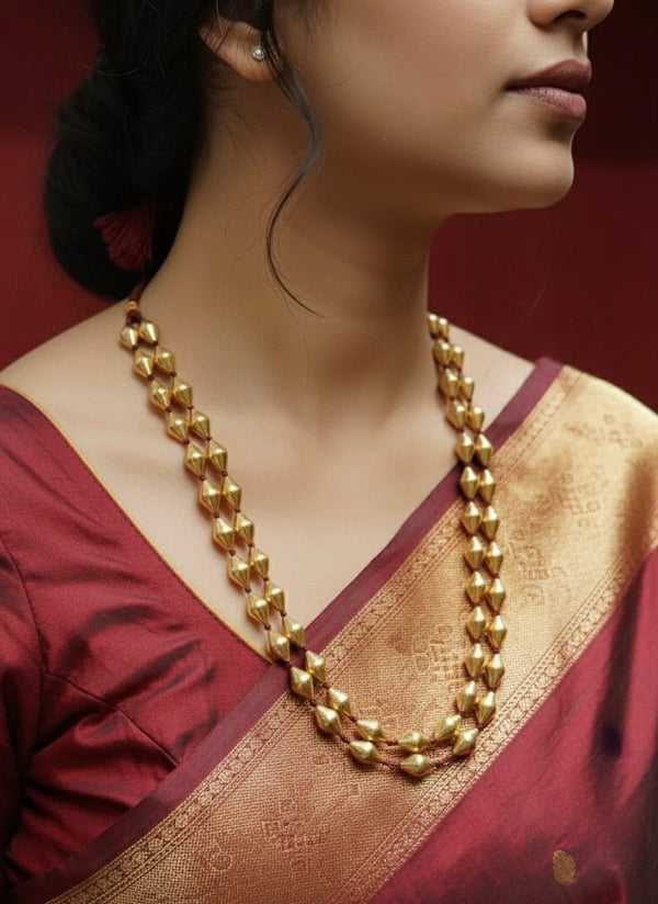 Woman wearing Gold plated silver dholki necklace handcrafted in a traditional layered necklace style with a maroon and gold saree