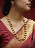 Woman wearing Gold plated silver dholki necklace handcrafted in a traditional layered necklace style with a maroon and gold saree