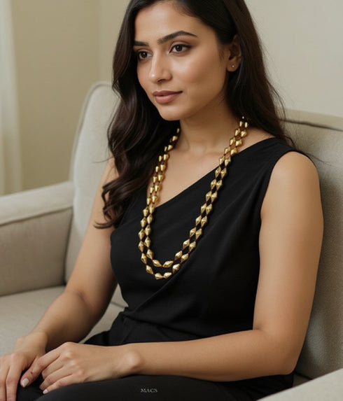 Woman wearing a black dress and gold plated 925 pure silver dholki necklace sitting on a couch.