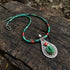 Necklace with green turquoise and red coral beads and a silver pendant on a wooden surface